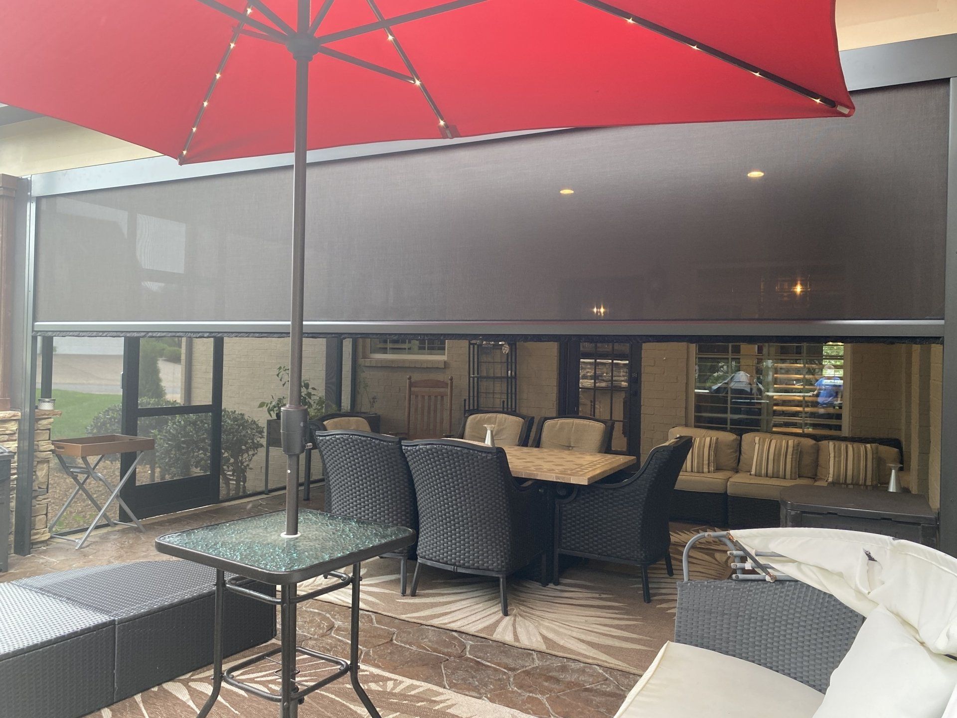 A patio with a red umbrella and a table and chairs.