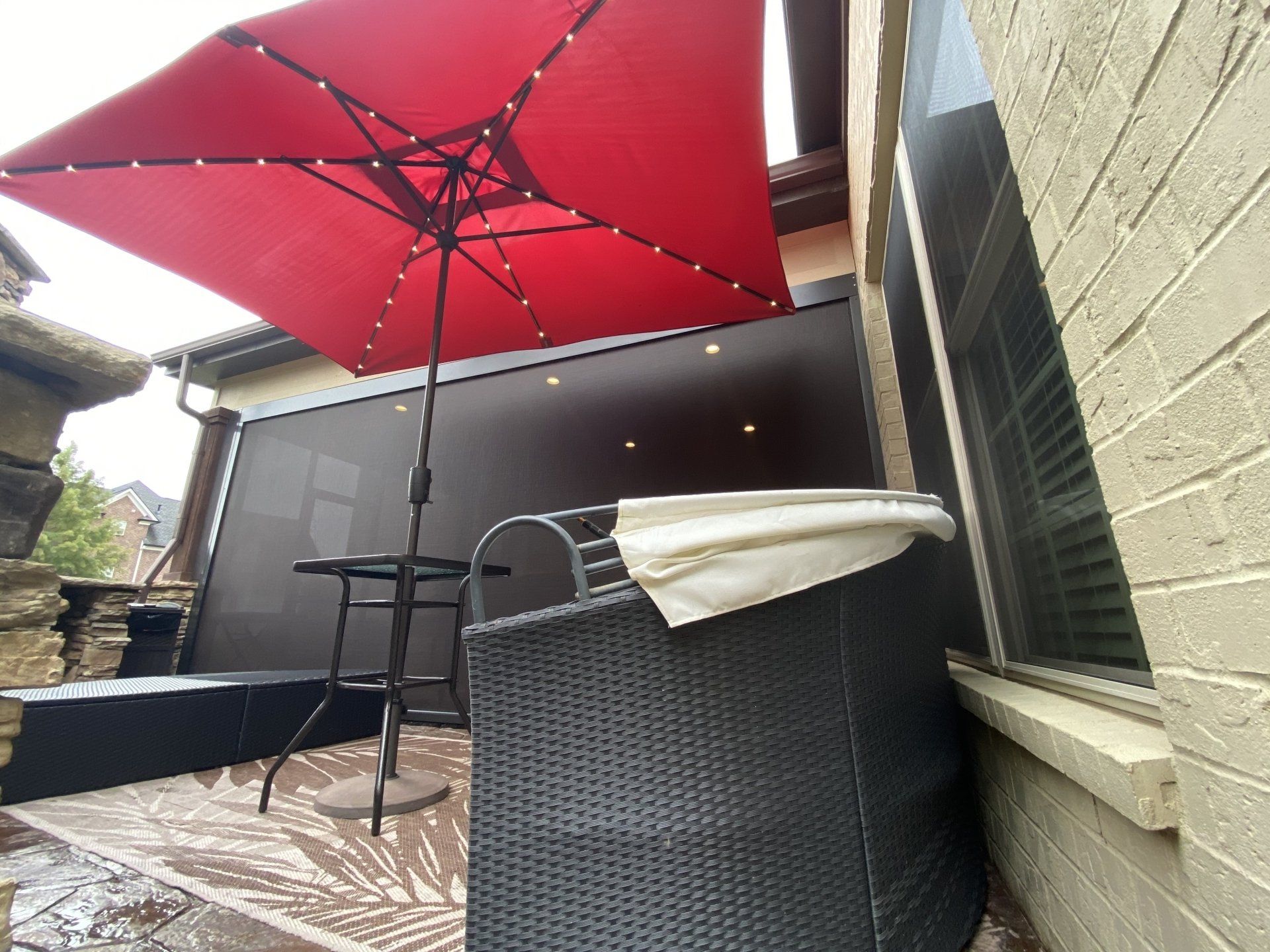 A red umbrella is sitting on a patio next to a table and chairs.