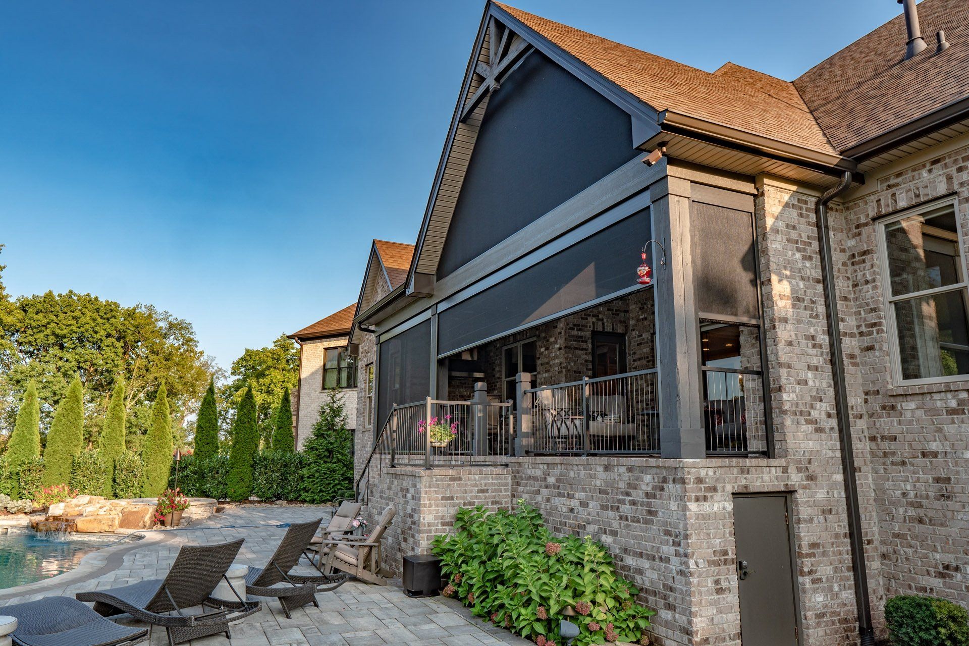 A large brick house with a screened in porch and a swimming pool.