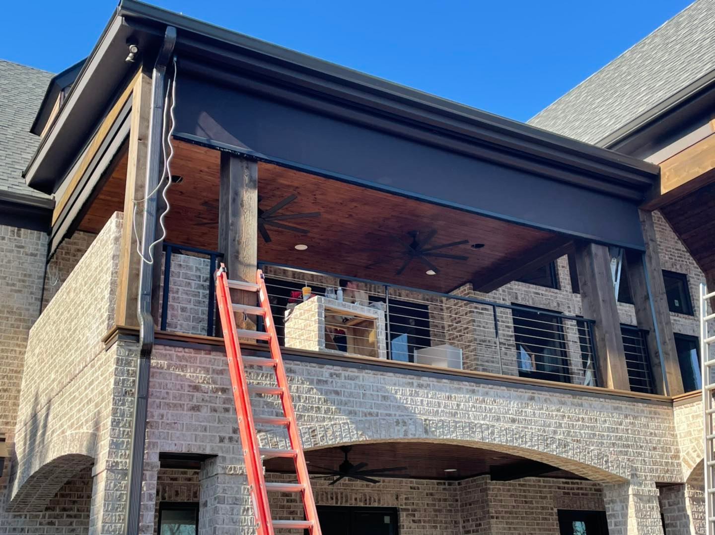 A man is standing on a ladder on the side of a brick building.