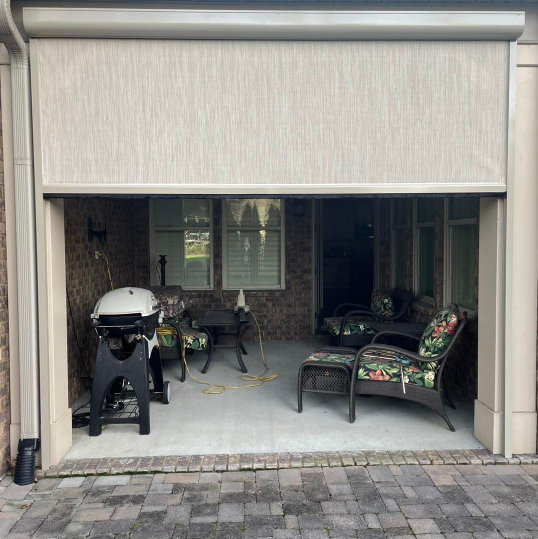A patio with a grill, chairs, and a table in a garage door.
