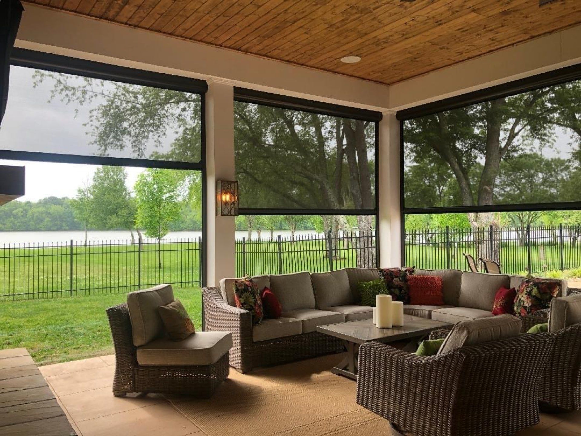 A screened in porch with a couch, chairs, and a table.