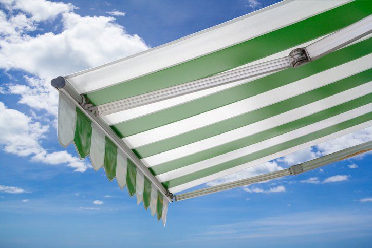 A green and white striped awning is against a blue sky.