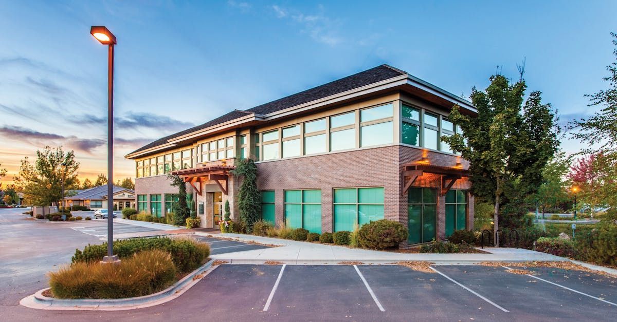 A large building with a lot of windows and a parking lot in front of it.