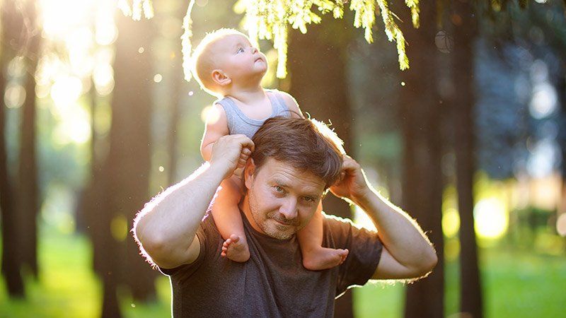 man holds child on his shoulders