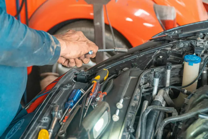 Mechanic using socket wrench on car engine.
