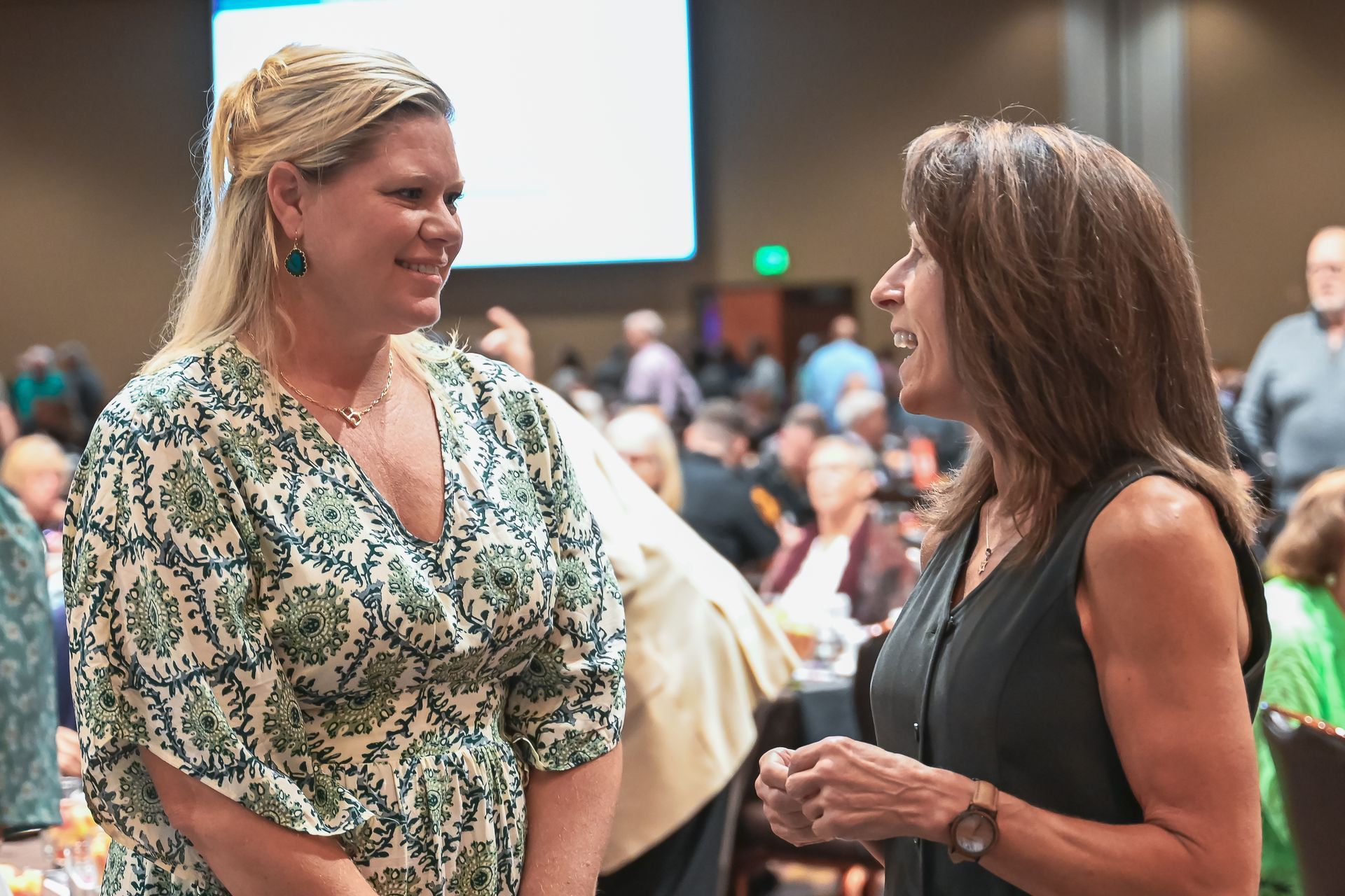 Two women are talking to each other in a crowded room.