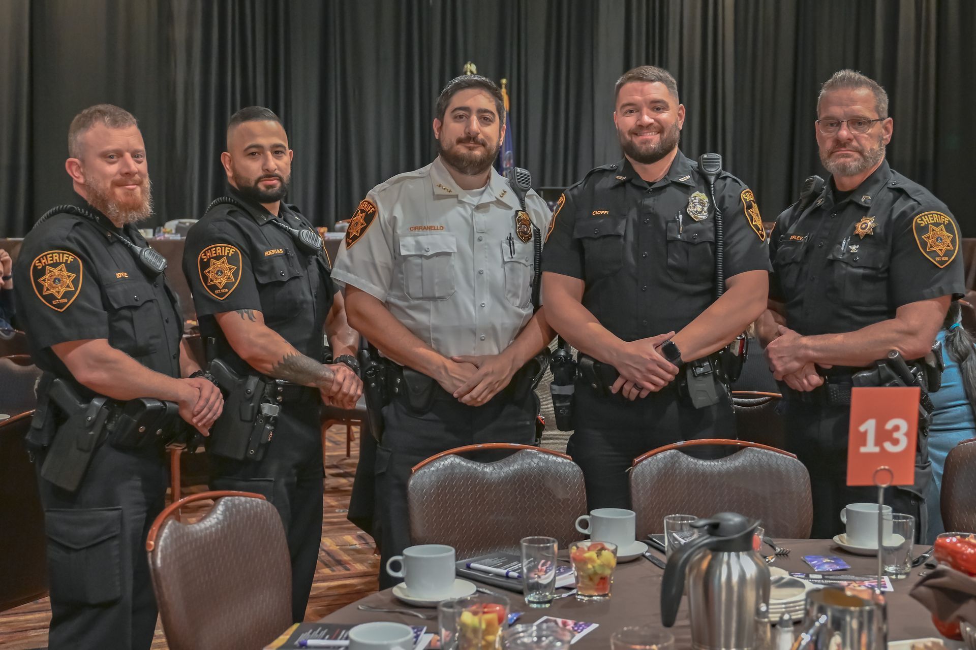 A group of police officers are posing for a picture in front of a table.
