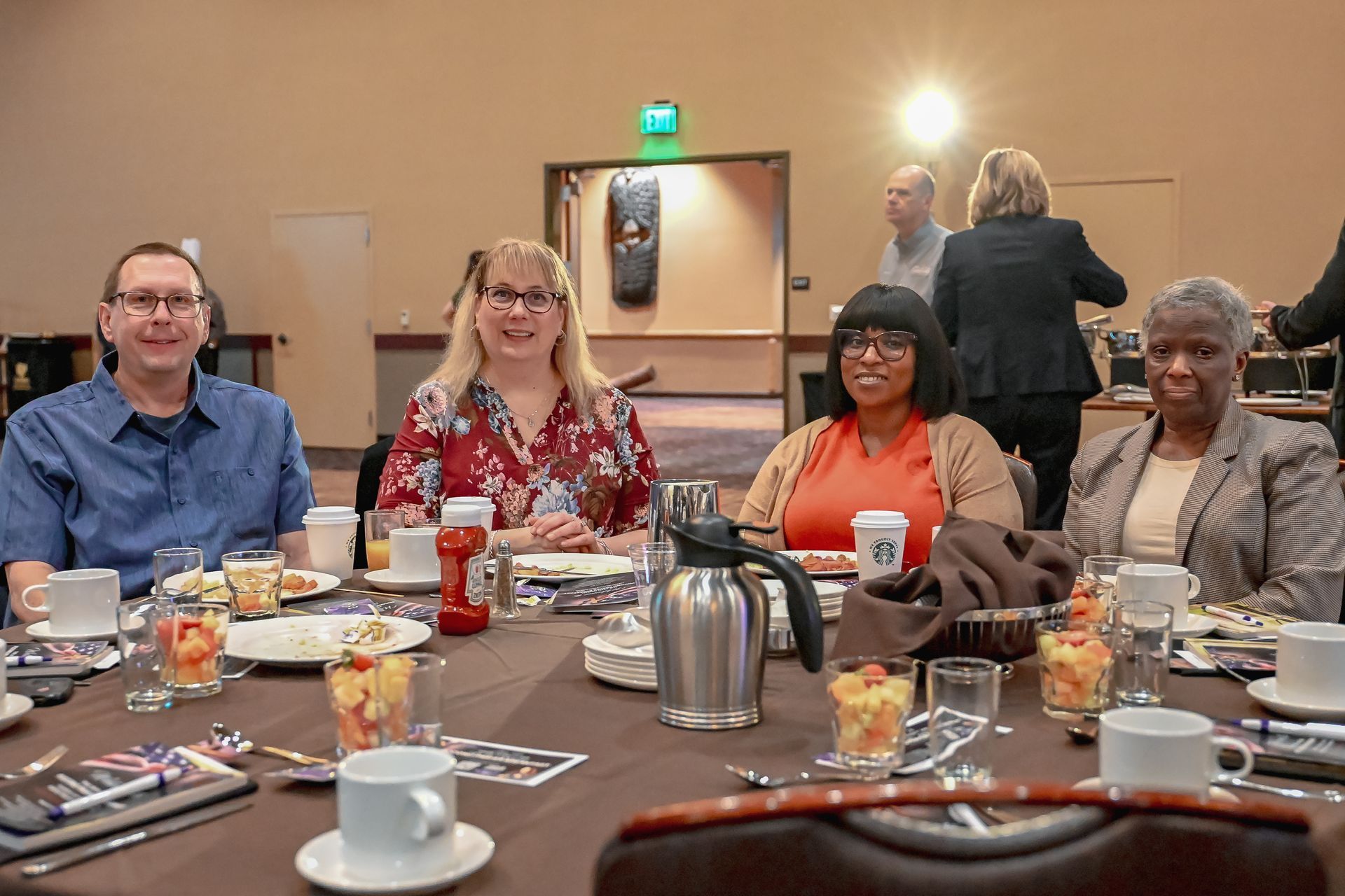 A group of people are sitting at a table with food and drinks.