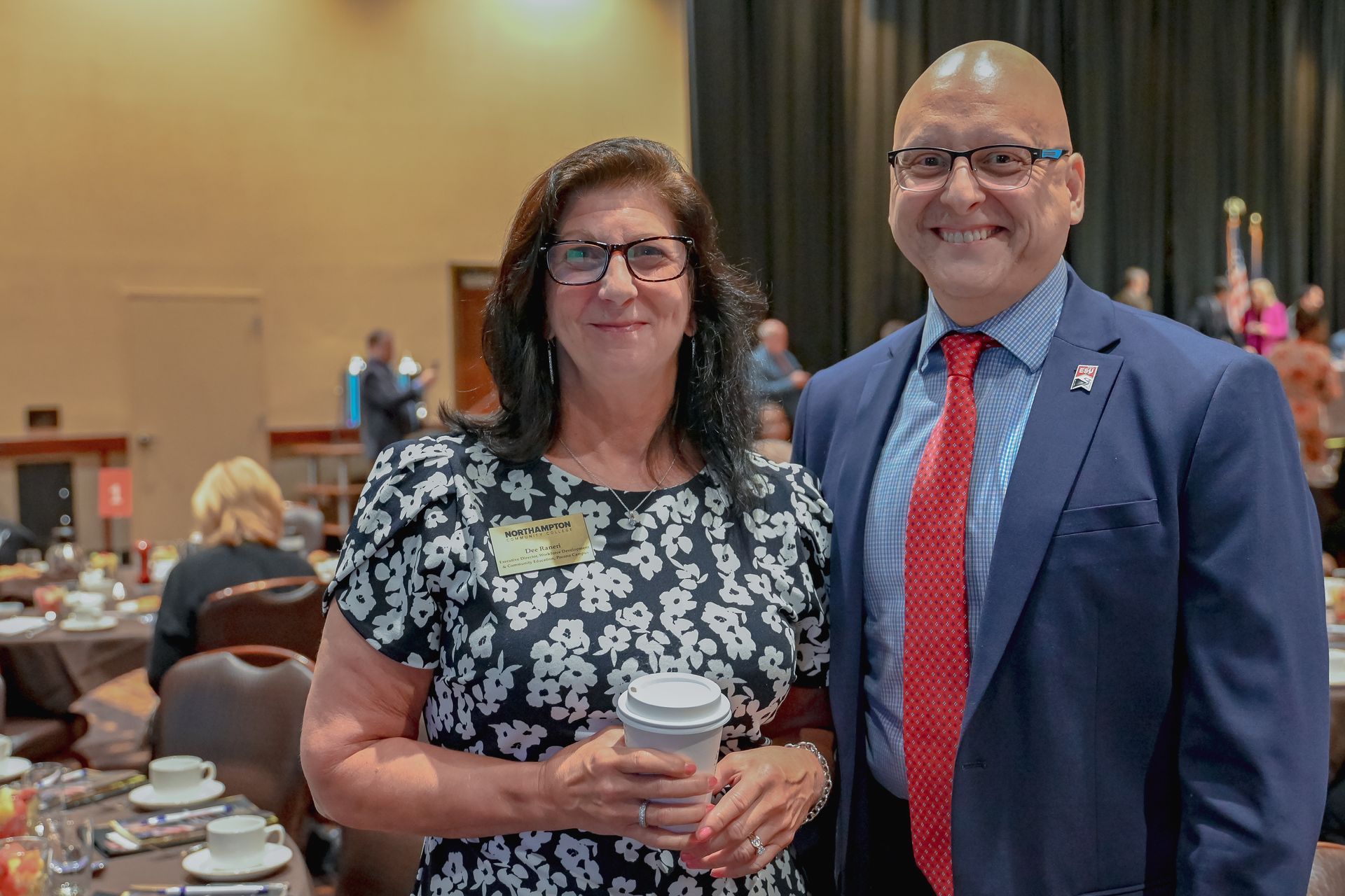 A man and a woman are posing for a picture at a conference.