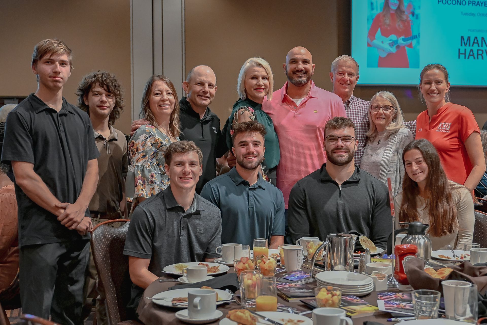 A group of people are posing for a picture at a table with food.
