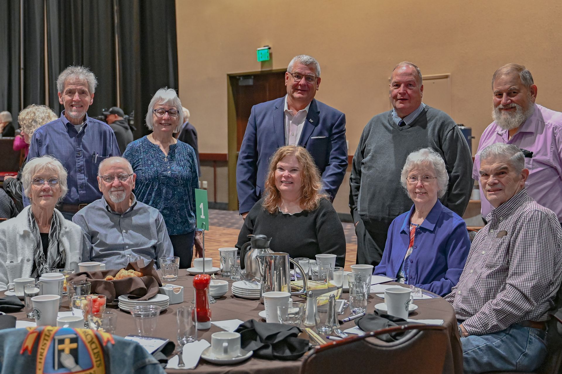 A group of people are posing for a picture while sitting at a table.