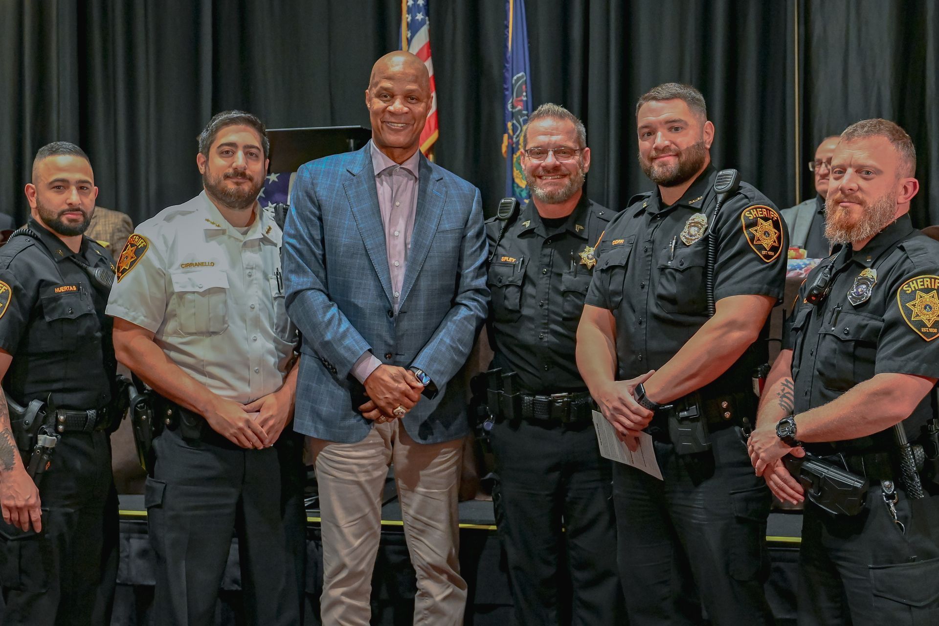 A group of police officers are posing for a picture with a man in a suit.
