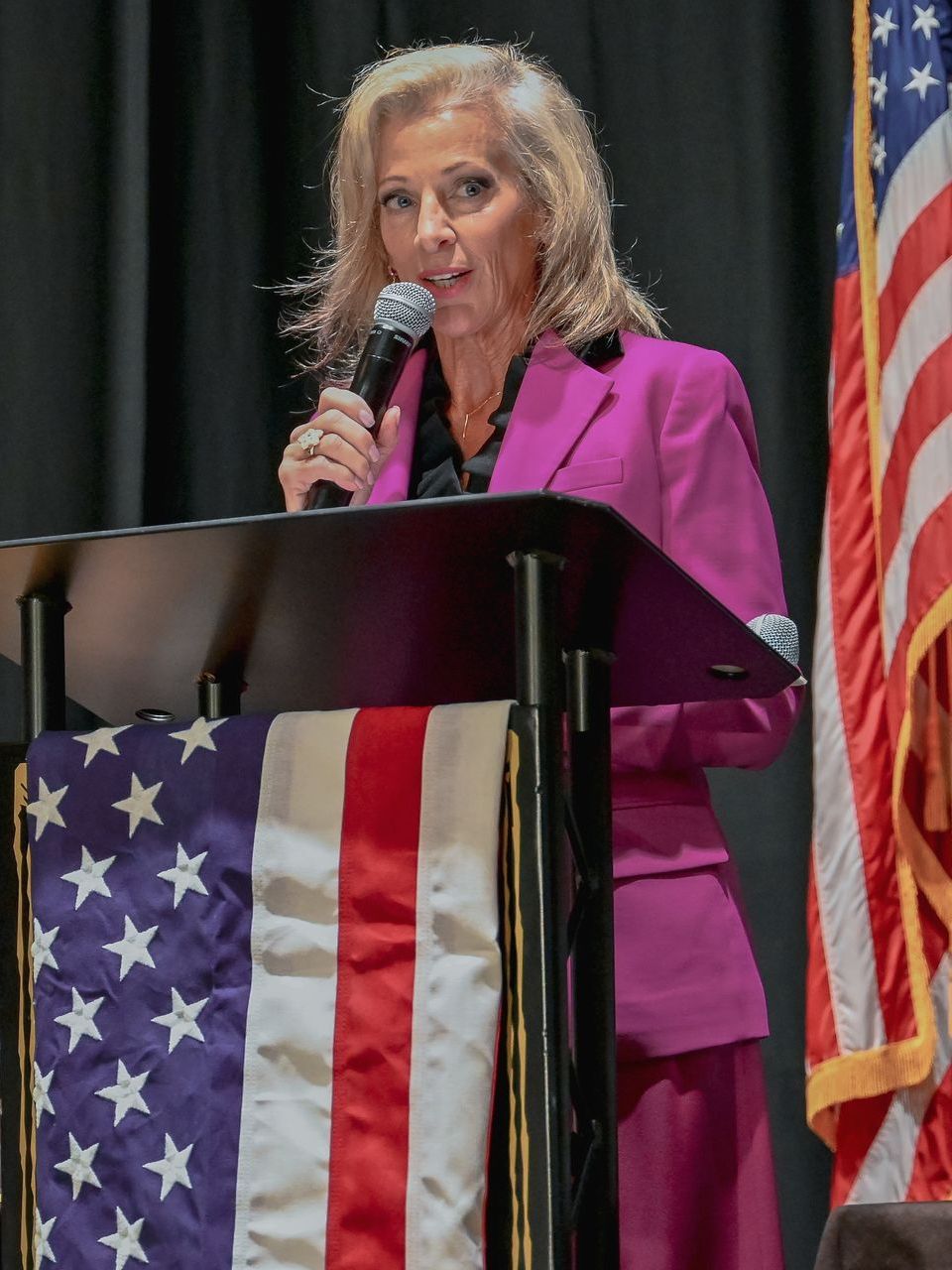 Charlie Trapasso stands at a podium holding a microphone