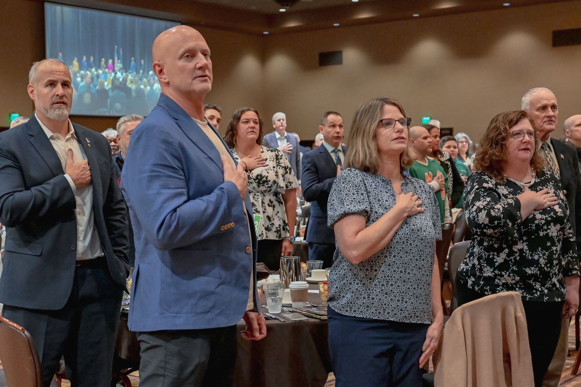 A group of people are standing in a room with their hands on their chests.