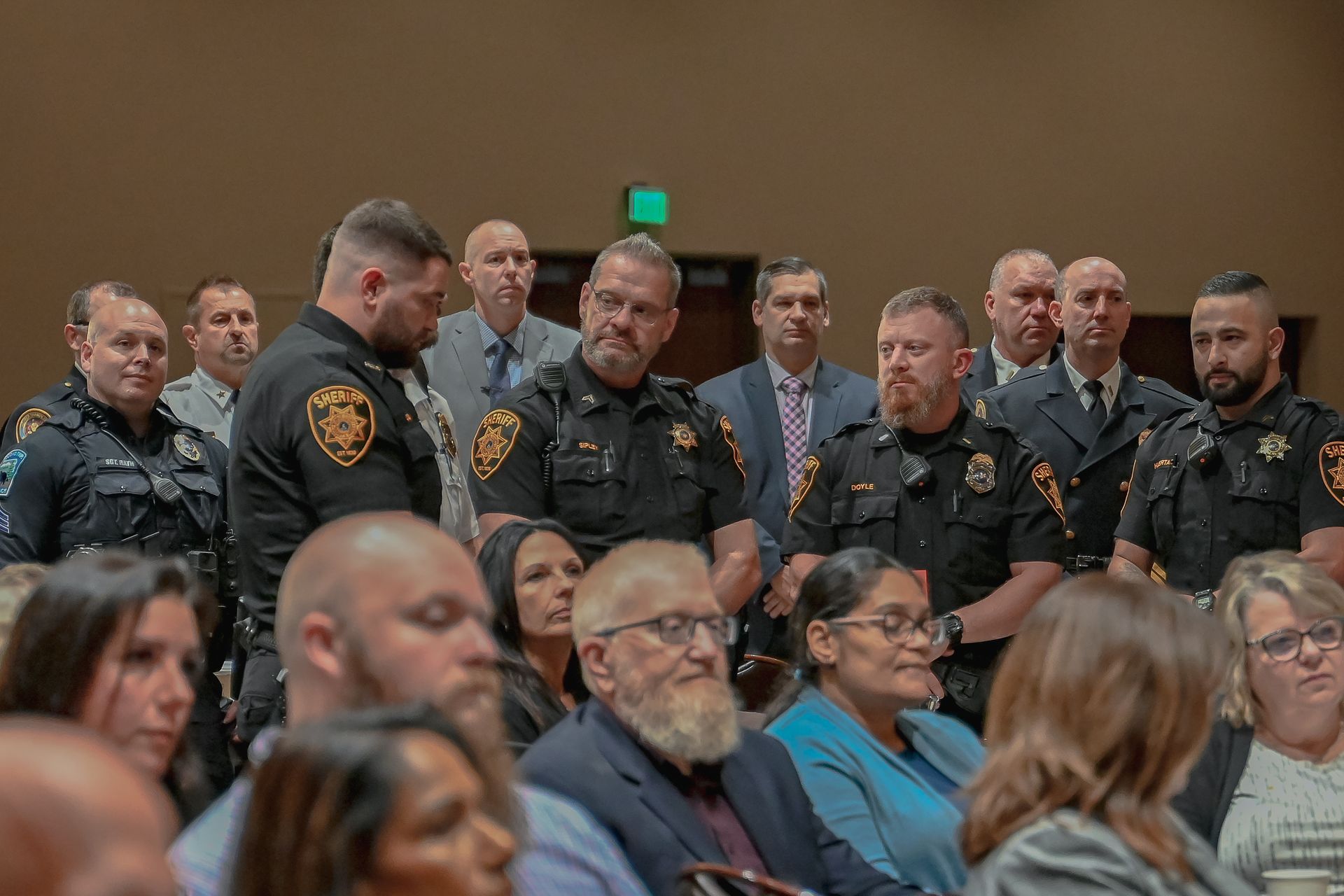 A group of police officers standing next to each other in front of a crowd of people.
