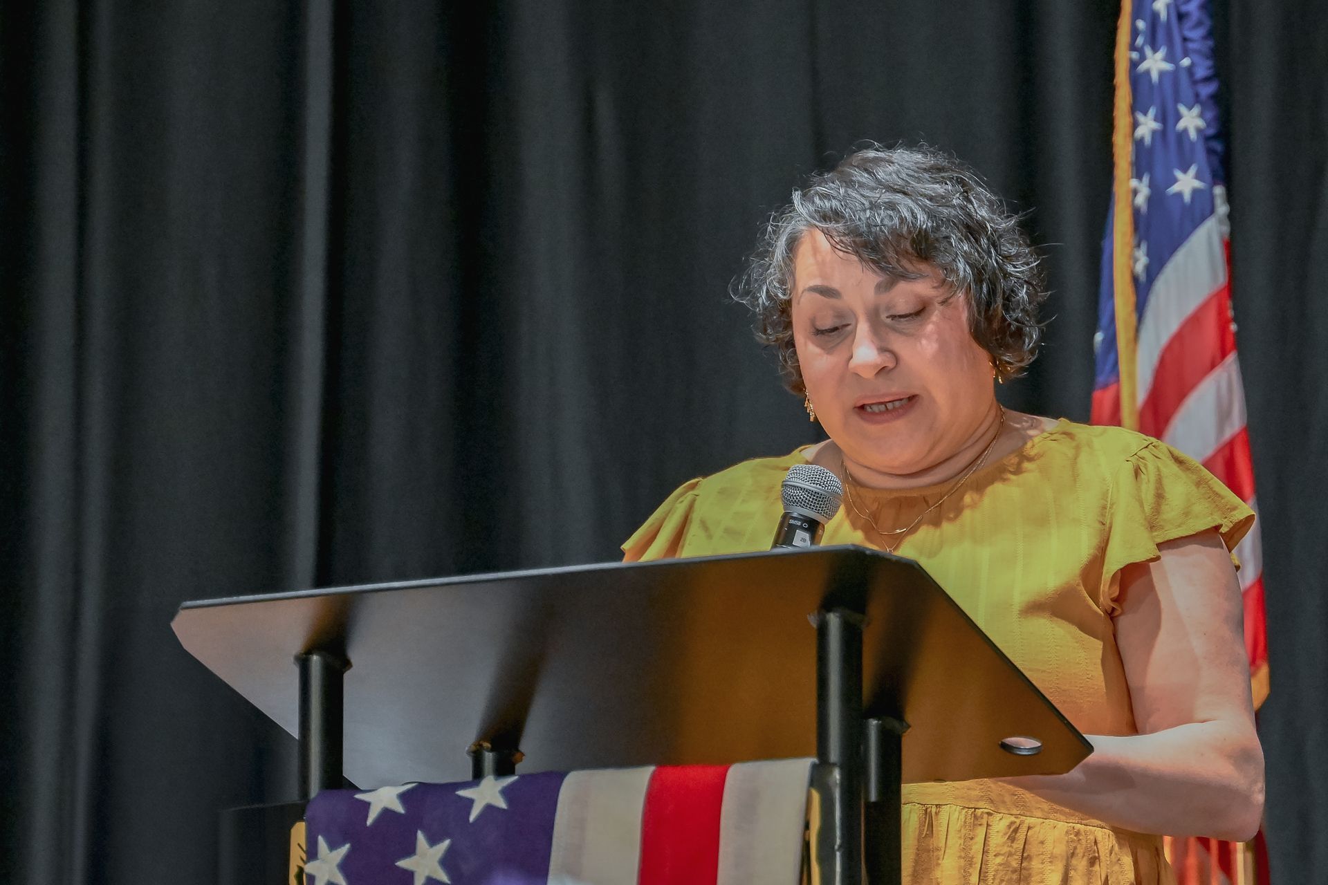 A woman is standing at a podium speaking into a microphone.