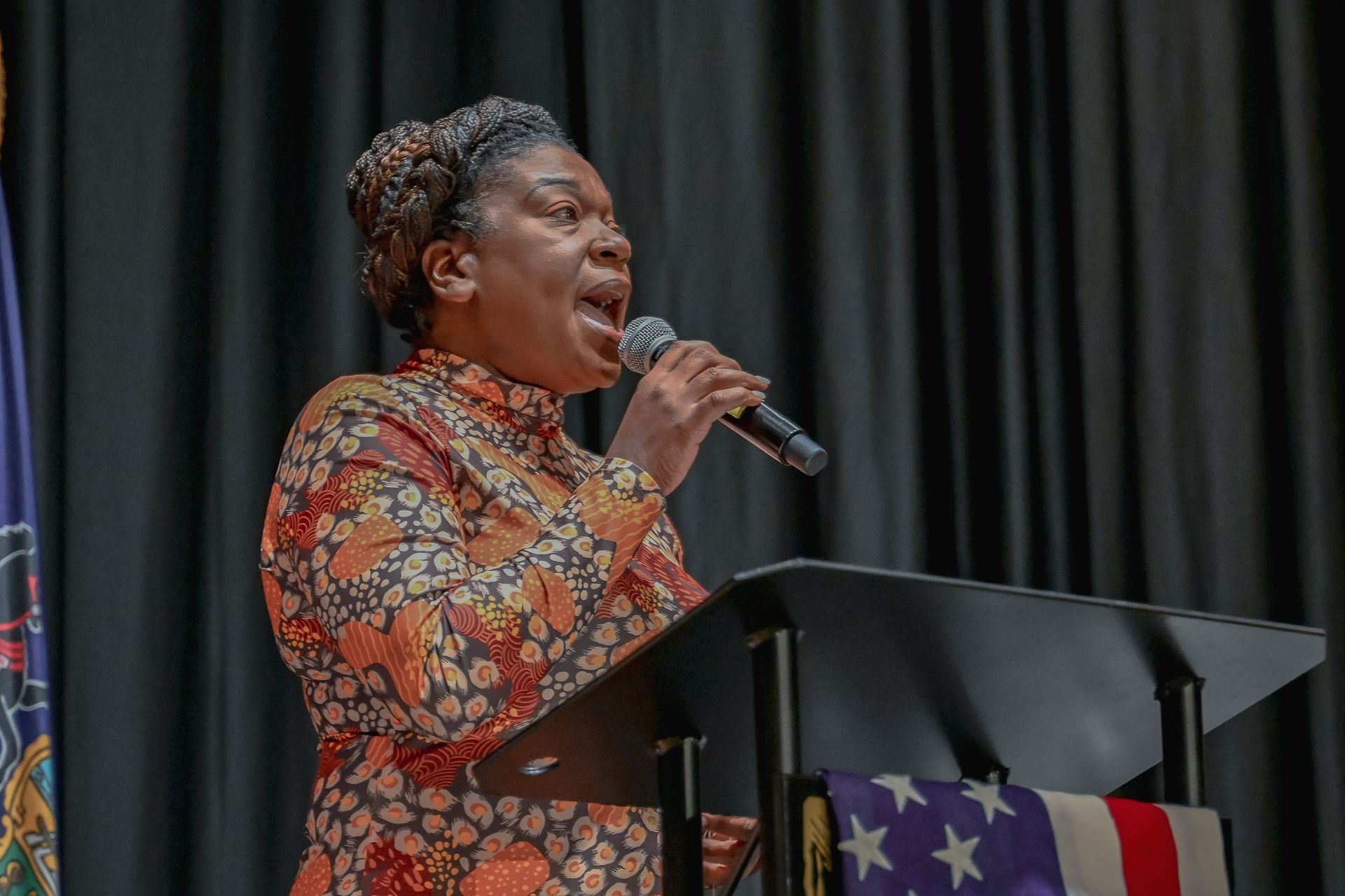 A woman is singing into a microphone while standing at a podium.