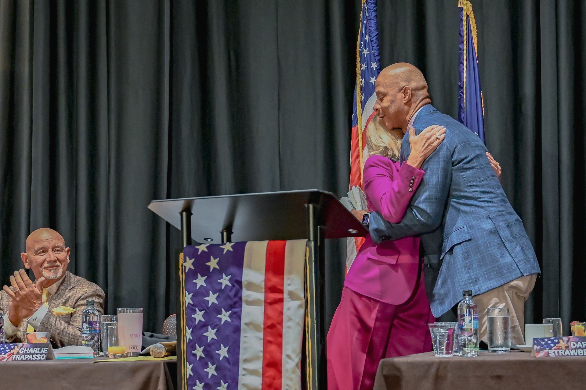 A man is hugging a woman in front of a podium.