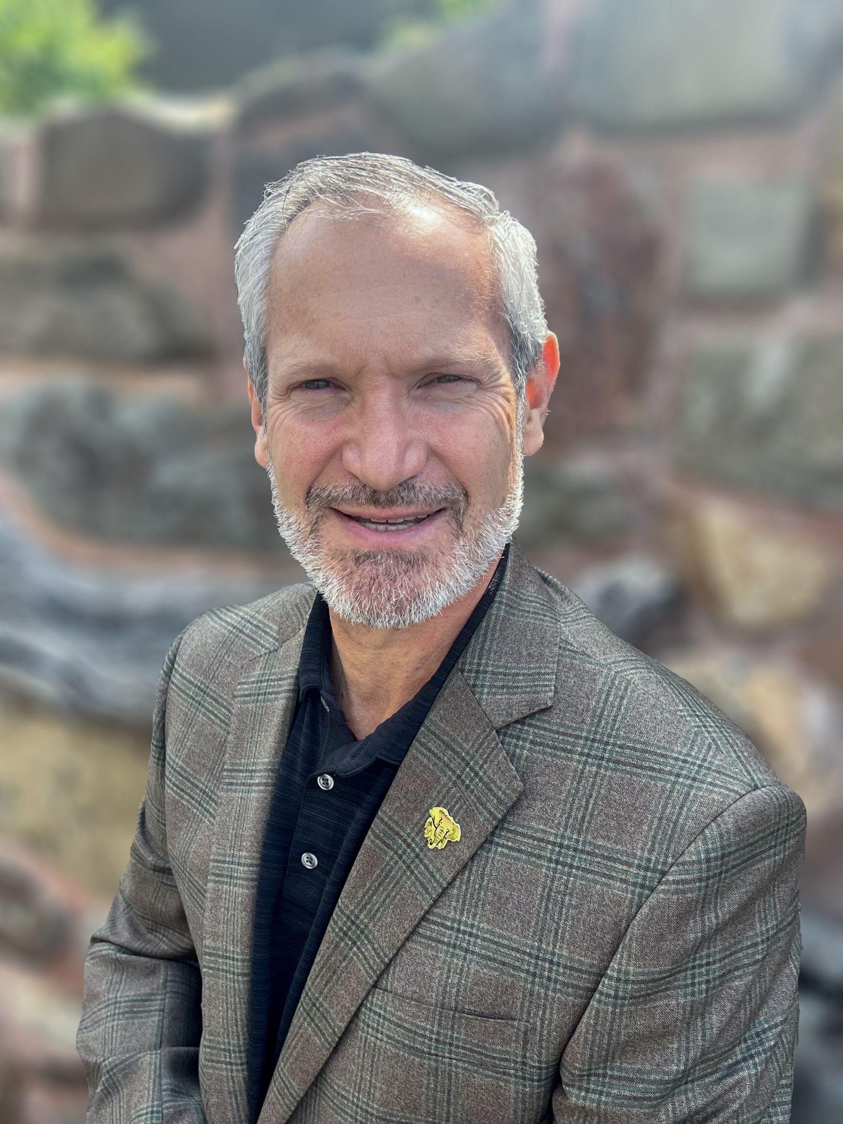 A man with a beard is wearing a suit and smiling for the camera.