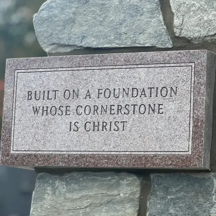 A stone plaque that says built on a foundation whose cornerstone is christ