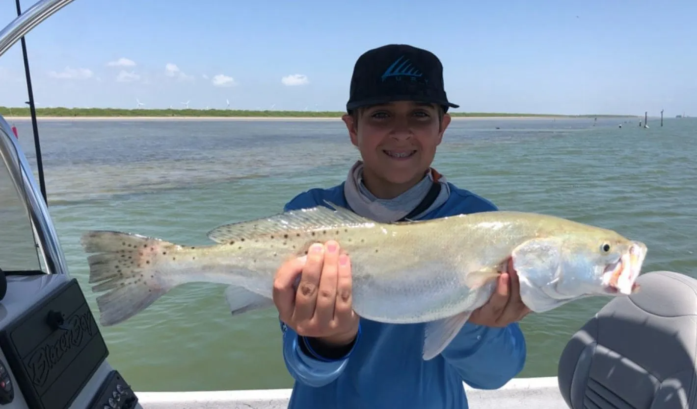 A man is holding a large fish in his hands on a boat.