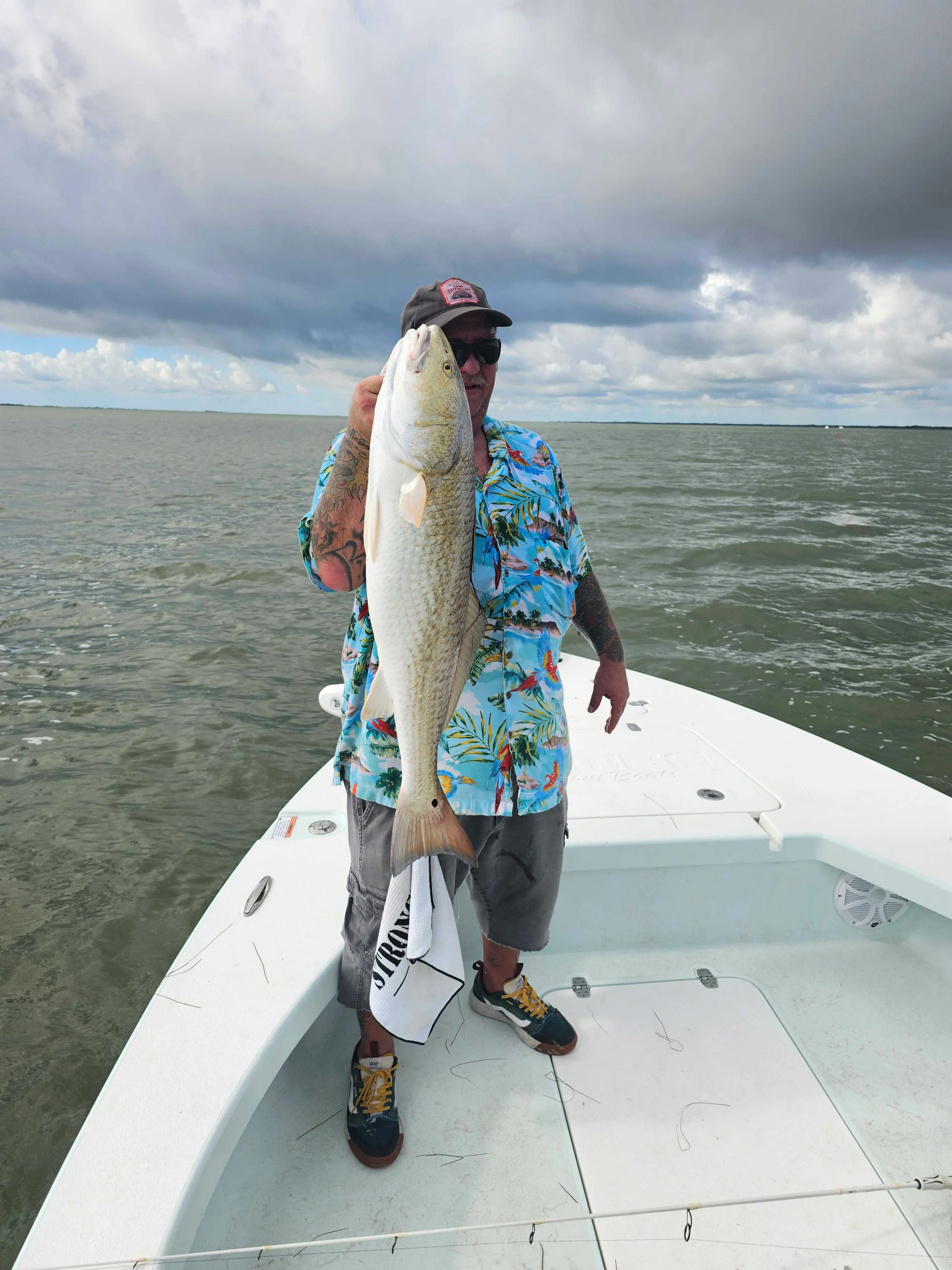 A man is standing on a boat holding a large fish.