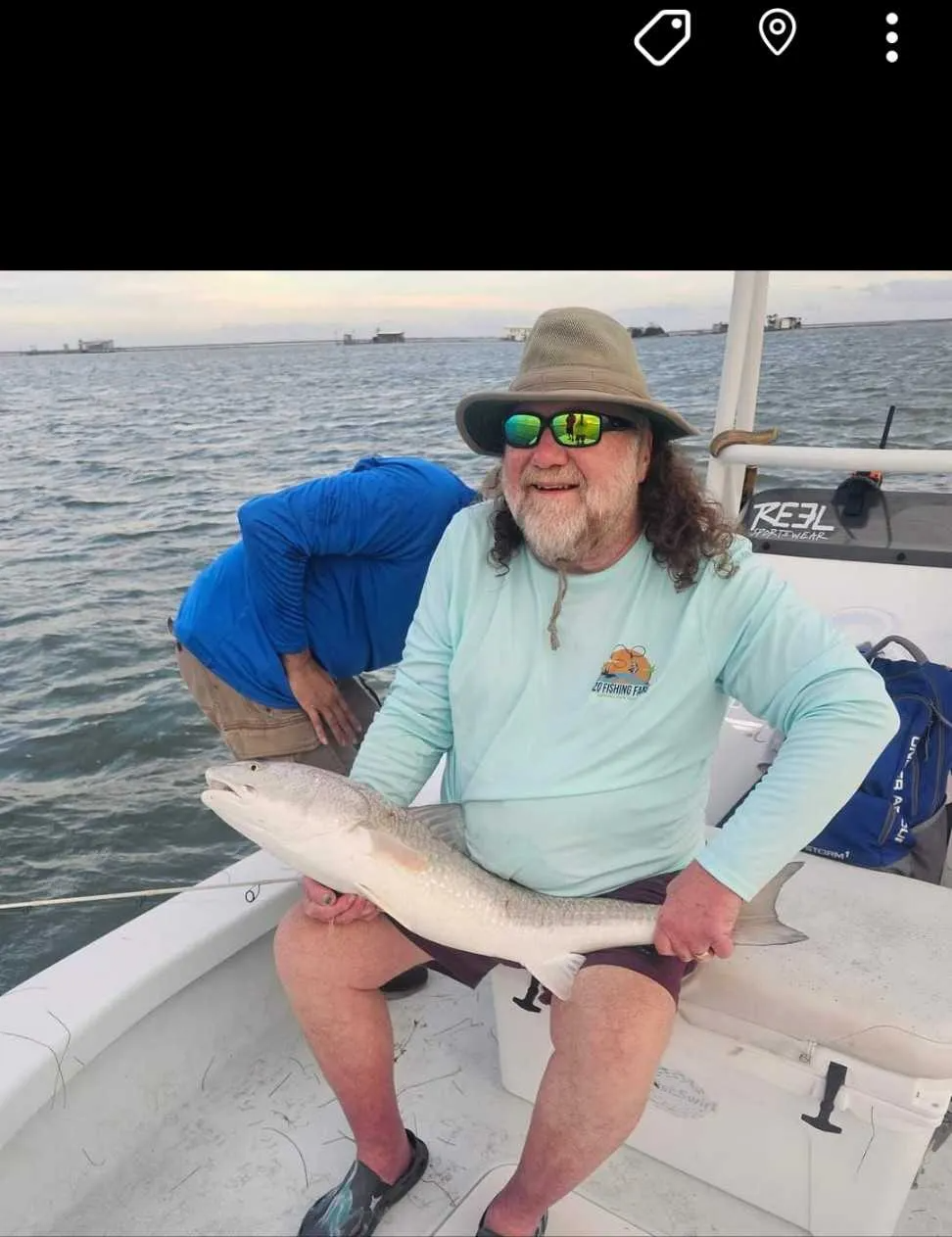 A man is sitting on a boat holding a fish