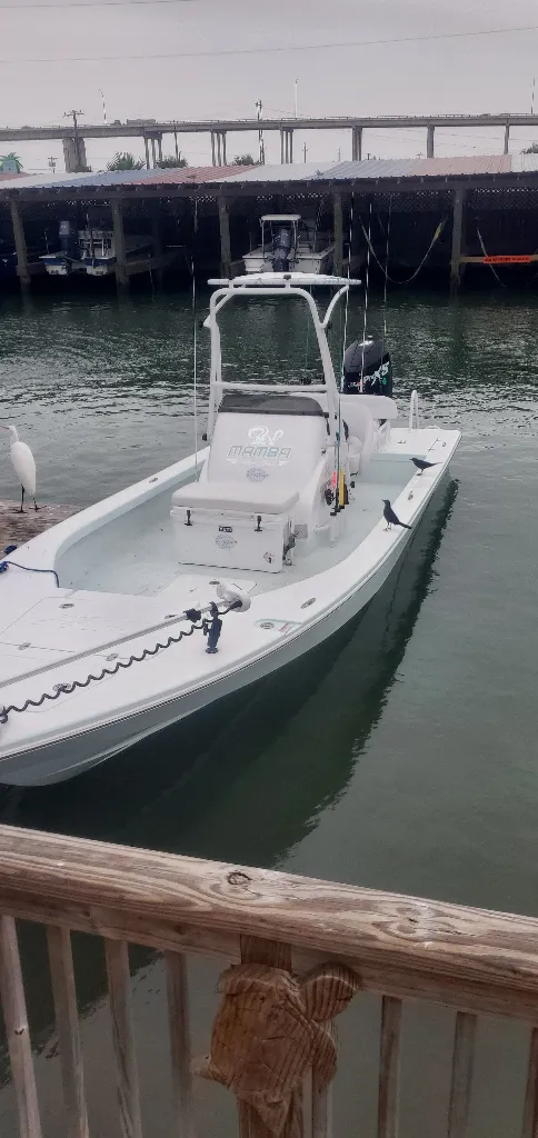 A white boat is docked in the water next to a wooden railing.