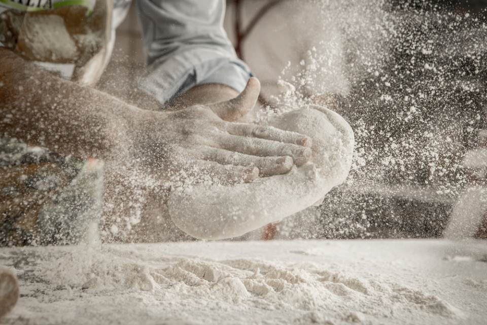 Pizzaiolo impegnato nell'apertura dell'impasto per pizza