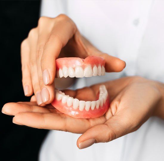 Dentist Holding Dentures — Louisville, OH — Louisville Dental Clinic