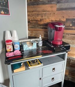 Coffee station with a red Keurig, cups, and supplies on a grey cabinet against wood paneling. |  Johnson's Automotive