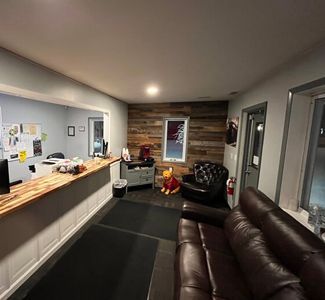 Interior of auto shop waiting area with dark leather sofa, wooden counter, and wood panel wall. |  Johnson's Automotive