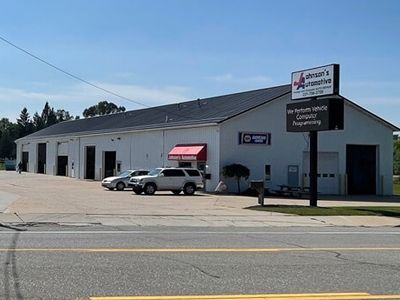 Wilson's Automotive building with a sign and two cars parked outside on a sunny day. | Johnson's Automotive