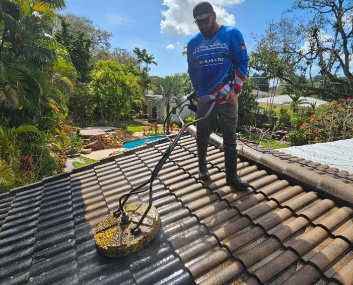 A man is cleaning a tile roof with a machine.