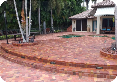 A brick patio with steps leading to a house and a pool.