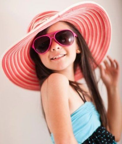 una bambina con un cappello rosso e degli occhiali da sole fucsia