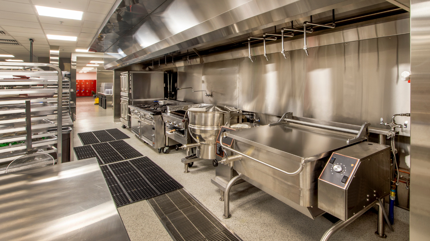 Commercial kitchen with stainless steel appliances and ventilation hood.