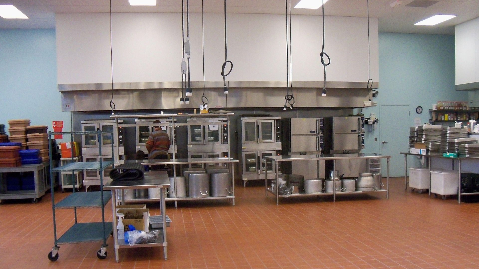 Commercial kitchen with stainless steel appliances, red tile floor.