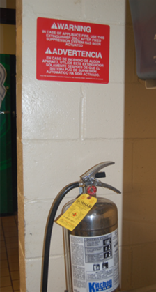 Red warning sign above a fire extinguisher on a white column.