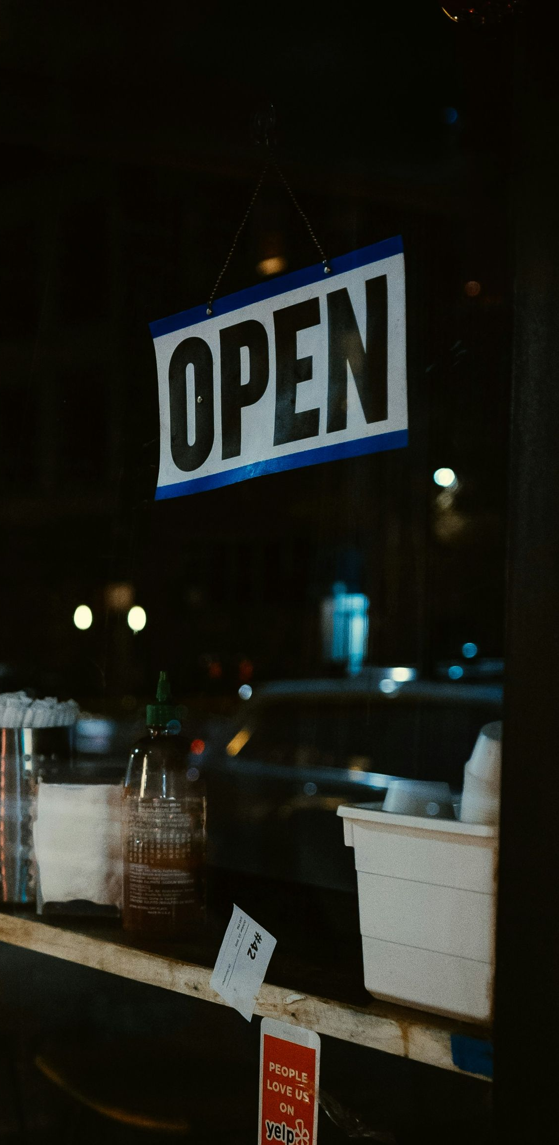Open sign glowing in a shop window at night