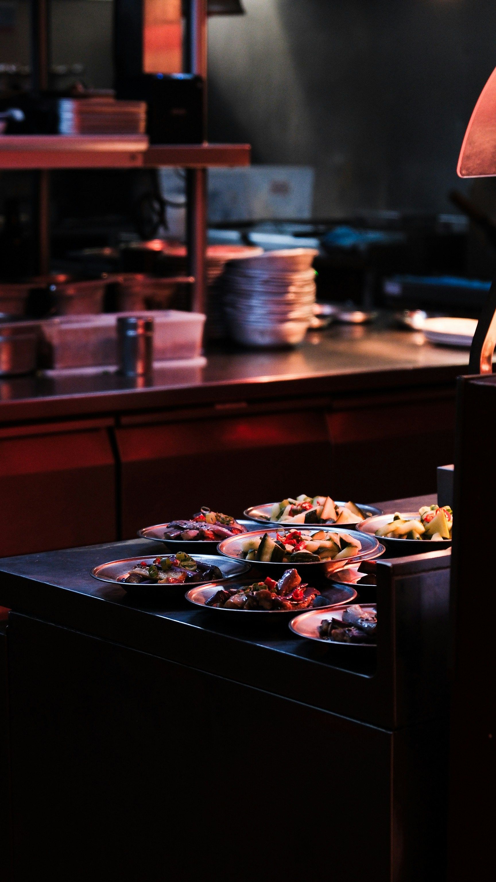 Plates of food on a dark countertop in a restaurant kitchen.
