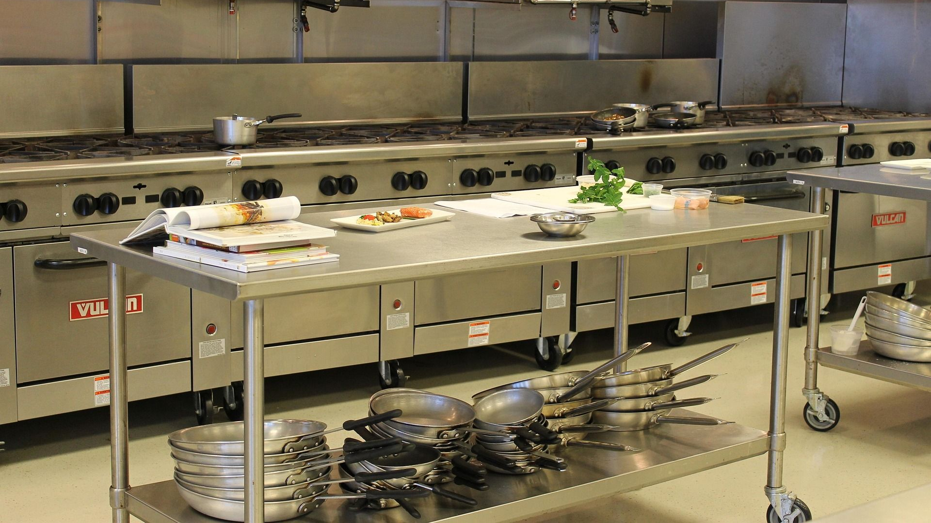 Commercial kitchen with stainless steel appliances and food preparation table.