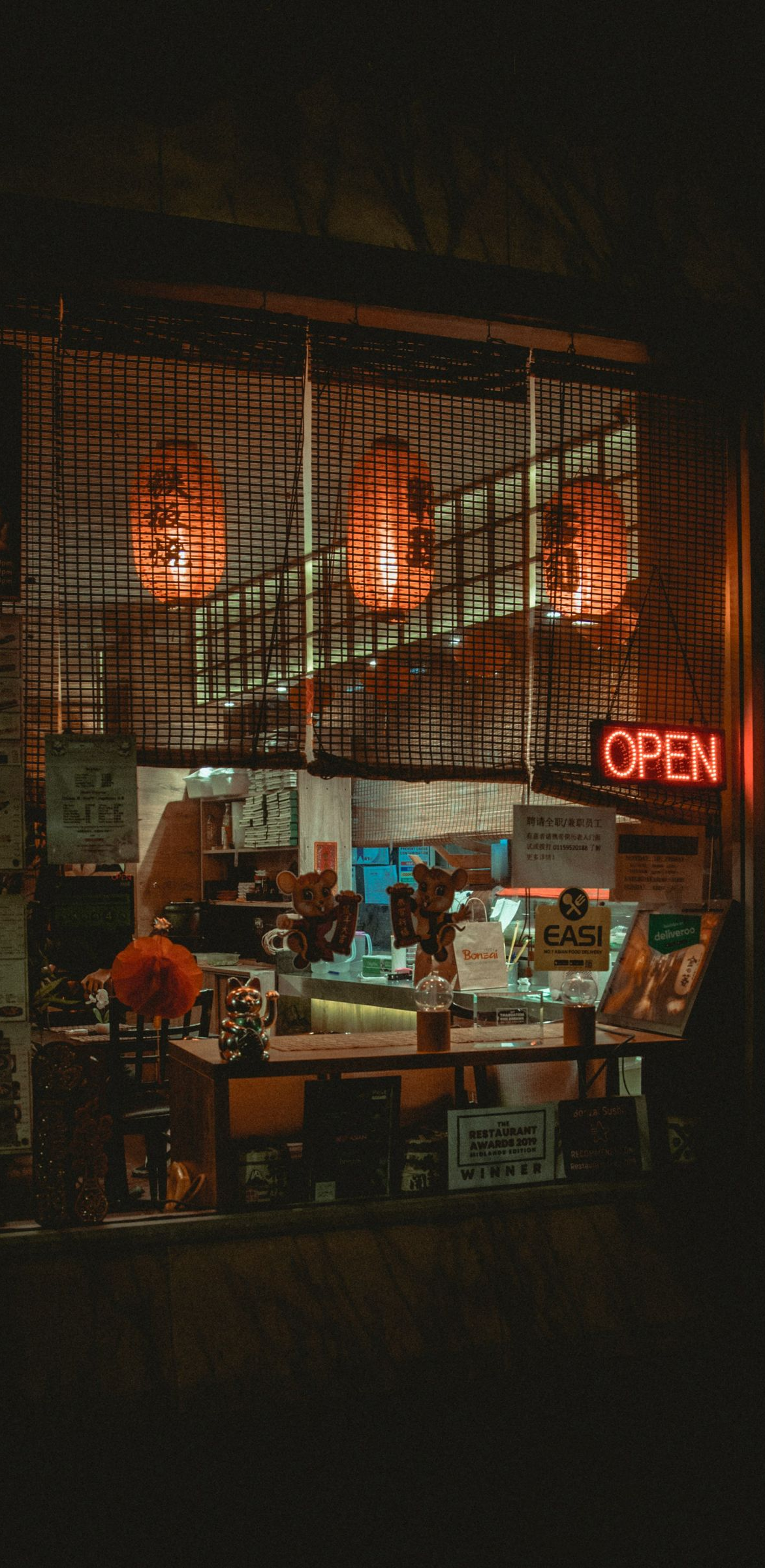 Dimly lit café at night with warm orange lights and a red neon “OPEN” sign.
