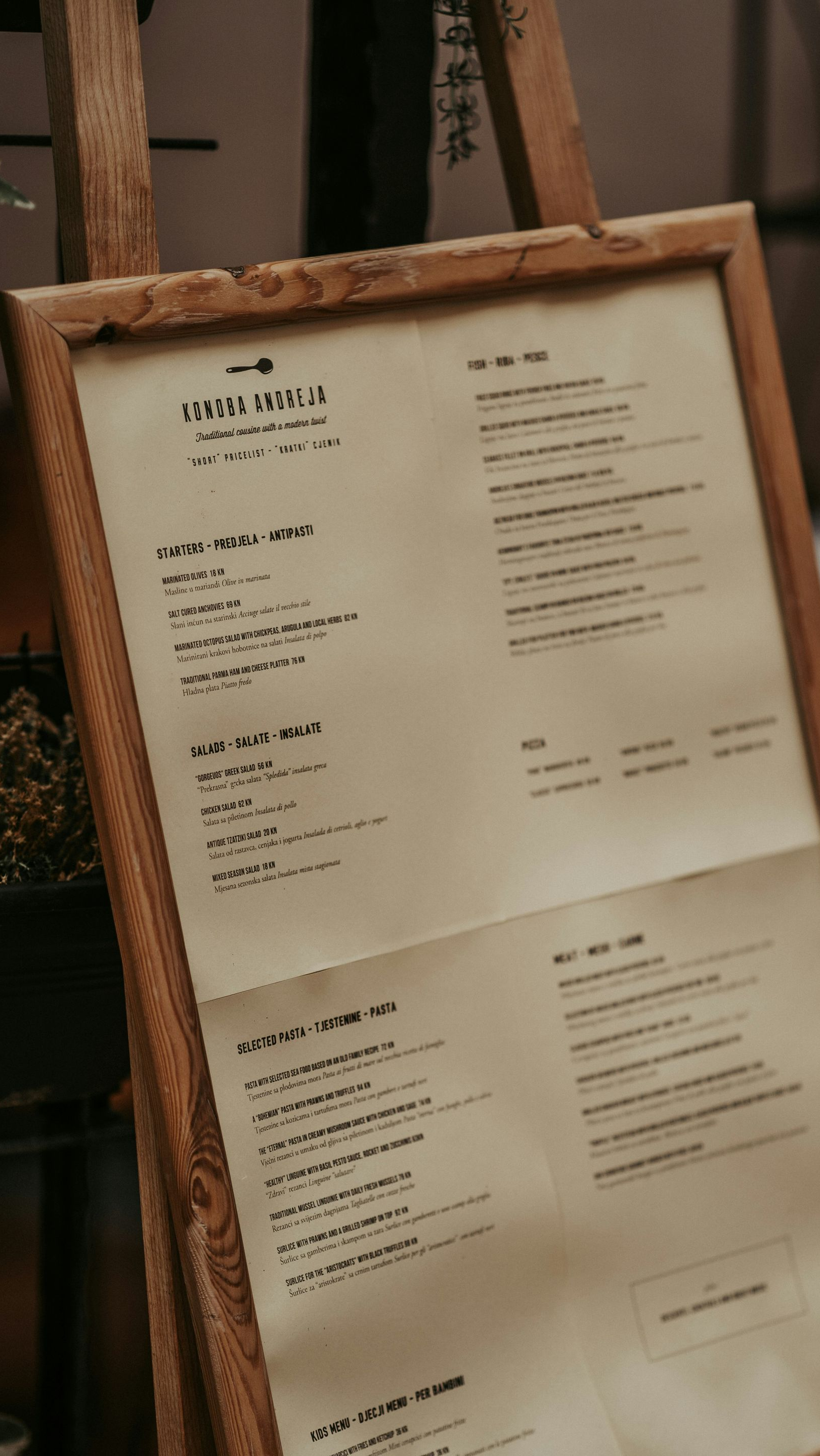 Wooden easel displaying a menu on aged paper with black text in a restaurant.