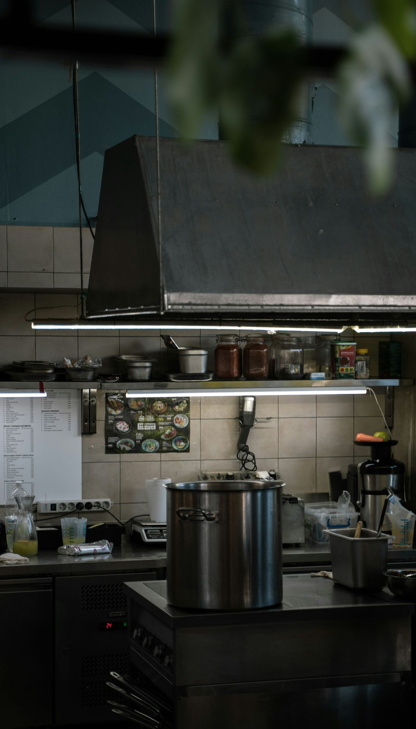 Commercial kitchen with stainless steel appliances and pots. Food prep area is dimly lit.