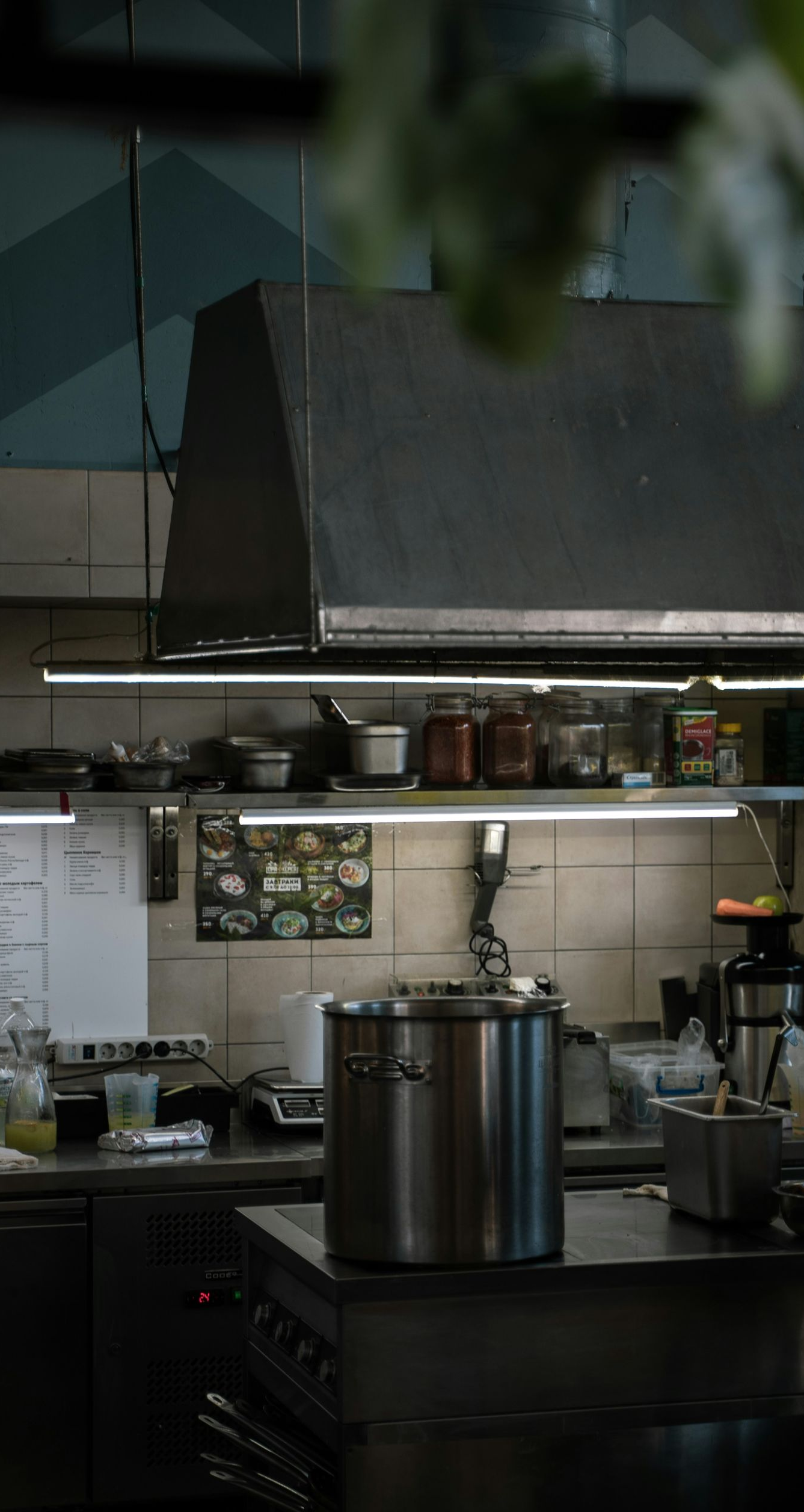 Commercial kitchen with stainless steel appliances and pots. Food prep area is dimly lit.