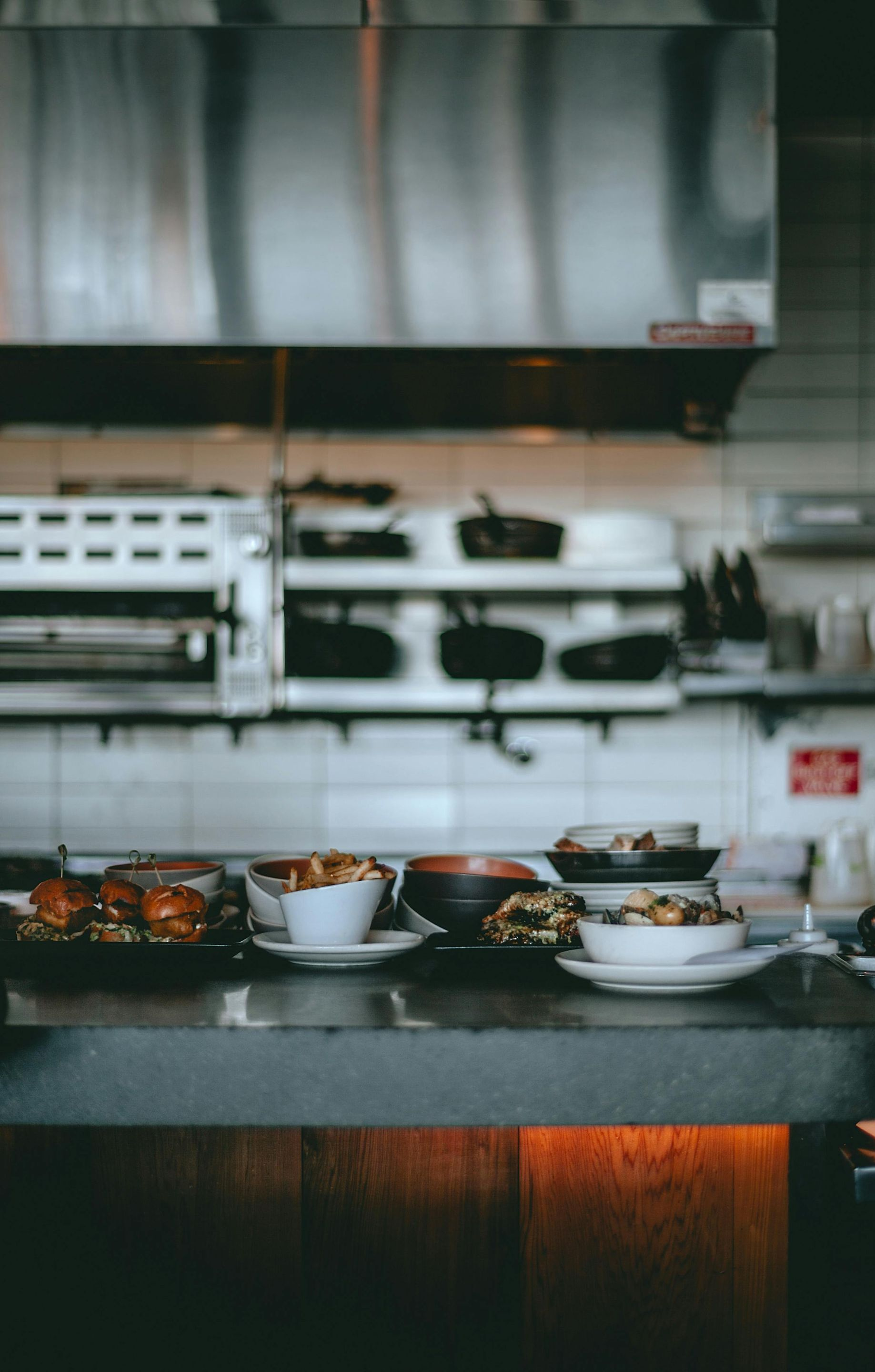 Countertop with bowls of food in a kitchen. Stainless steel hood and shelves in the background.