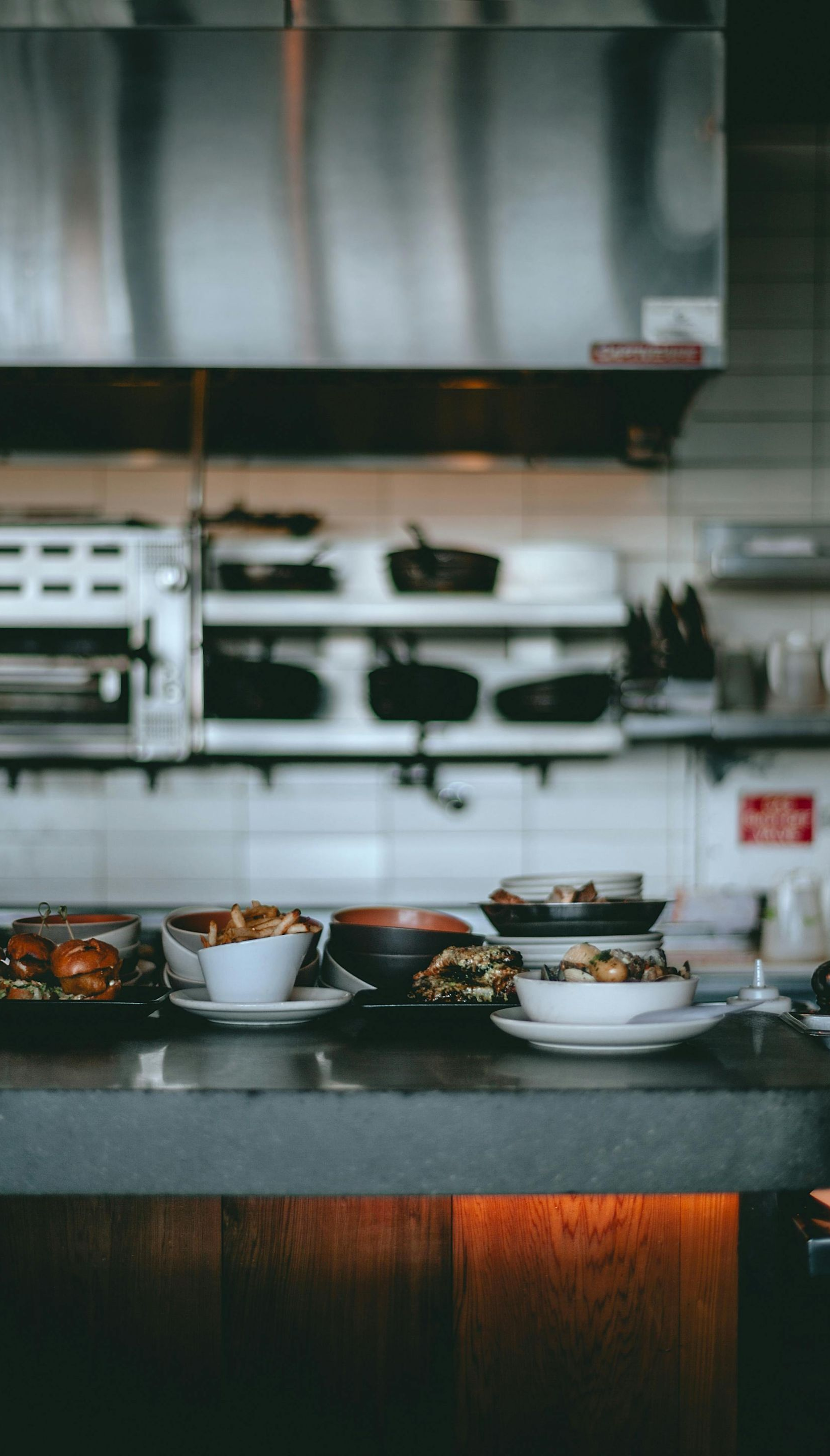 Countertop with bowls of food in a kitchen. Stainless steel hood and shelves in the background.