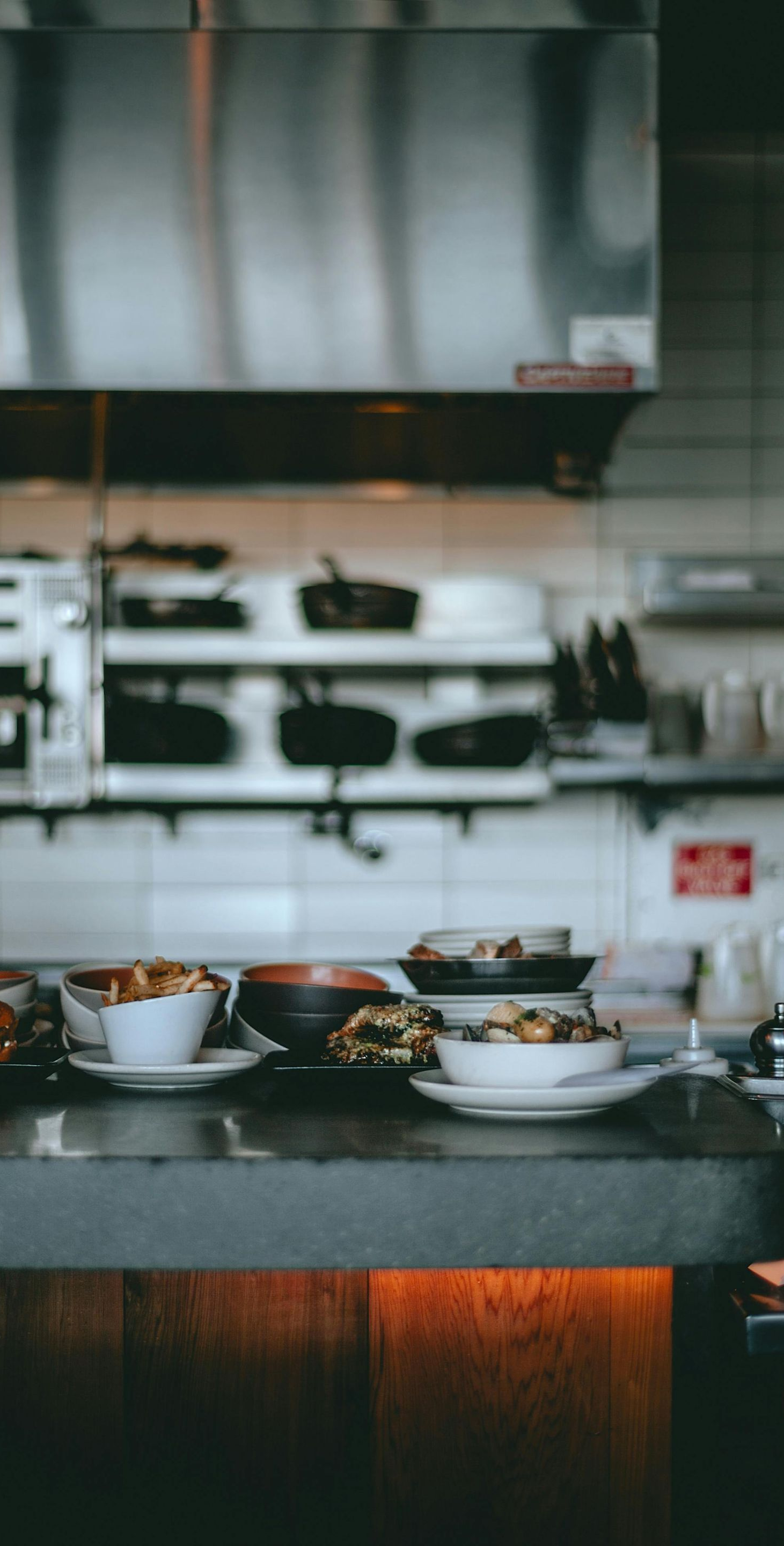 Bowls of food on a counter in front of a restaurant kitchen.